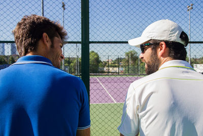 Tennis players sitting against net at court