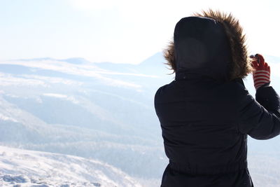 Rear view of man standing on mountain against sky