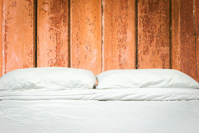 Pillows on bed against wooden wall