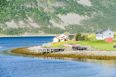 House by lake and buildings against mountain