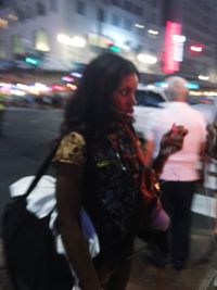 Woman standing on illuminated street at night