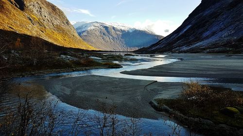 Scenic view of lake by snowcapped mountains against sky