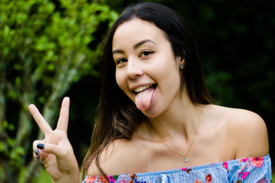 Portrait of young woman showing peace sign