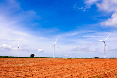 Windmills on field against sky