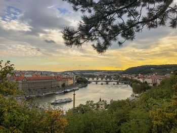 Bridge over river in city against sky at sunset