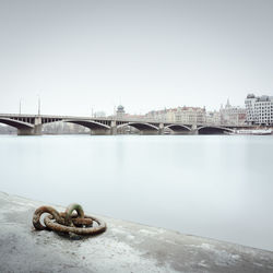 Bridge over river in city against sky