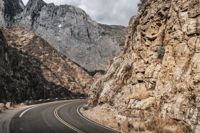 Road passing through rock formation against sky