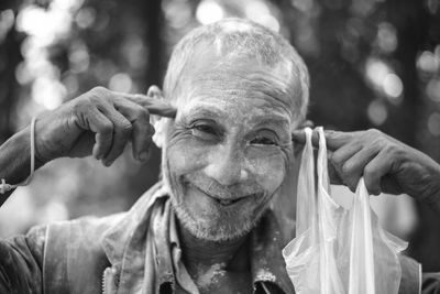 Close-up portrait of smiling senior man gesturing outdoors