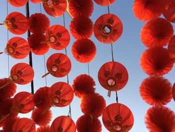 Low angle view of lanterns hanging against orange sky