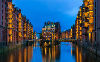 Canal amidst buildings in city at dusk