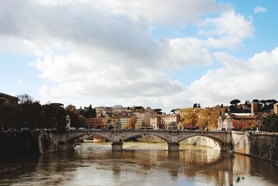 Arch bridge over river against sky in city