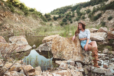 Woman sitting on rock by the lake