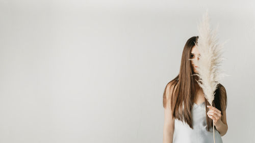 Portrait of a beautiful girl with long hair with a bouquet of pampas grass on her face.