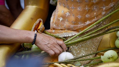 Close-up of hand keeping flower on buddha