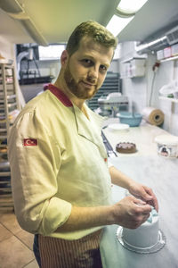 Portrait of smiling chef making cake in kitchen 