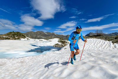 Man skiing on snow covered field against sky