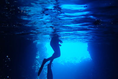 Low section of person wearing diving flippers swimming undersea