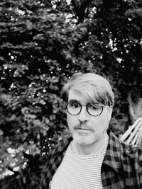 Portrait of mature man wearing eyeglasses against trees