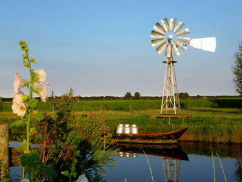 Traditional windmill on lake against sky