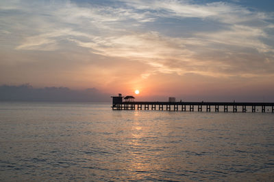 Silhouette pier over sea against sky during sunset
