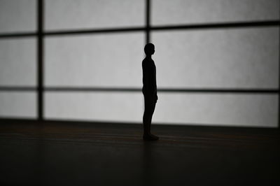 Silhouette woman standing against wall