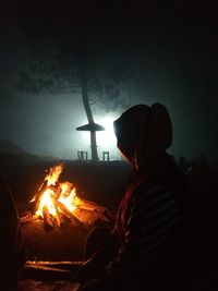 Silhouette woman with bonfire against sky at night