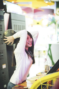 Cheerful young woman holding ball at amusement arcade