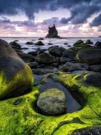 Rocks on beach against sky during sunset