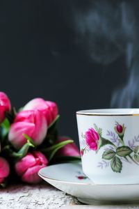 Close-up of coffee cup and pink flowers on table