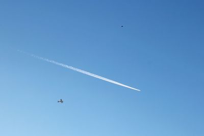 Low angle view of airplane flying against clear blue sky