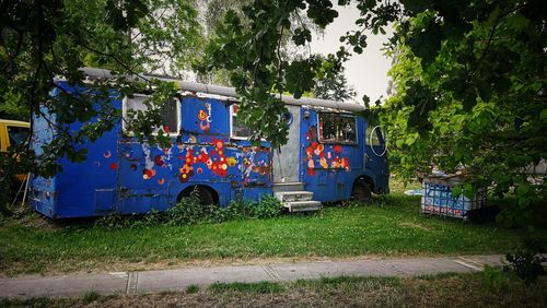 Information sign on field by road against trees