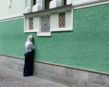 Rear view of a woman standing against wall