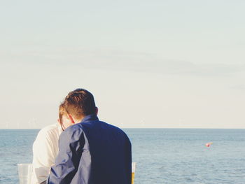 Rear view of man standing in sea against sky