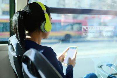 Rear view of man using mobile phone in bus