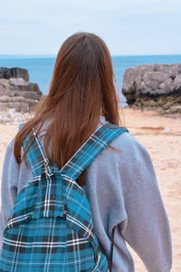 Rear view of woman with backpack standing on beach