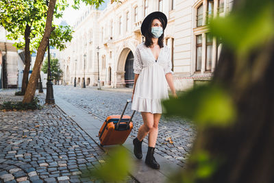 Full length of woman wearing mask walking on street in city