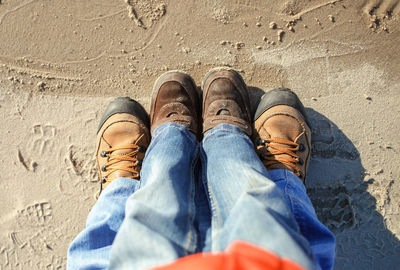 Low section of couple standing on sand at beach