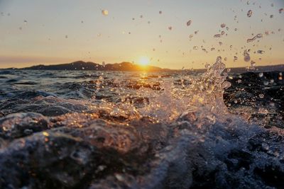 Close-up of splashing water against sky during sunset