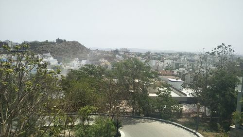 Trees and buildings in town against clear sky