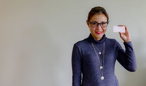 Portrait of smiling young woman standing against wall