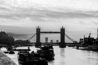 Boats moored at harbor against cloudy sky