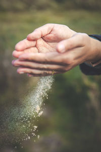 Cropped hands of man holding sand outdoors