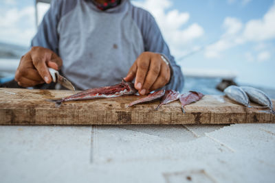 Midsection of man working on cutting board