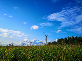 Wind turbines on field against sky