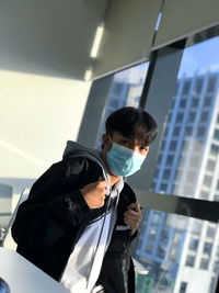 A young guy wearing surgical mask at work to prevent spreading or contracting the covid-19 virus