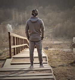 Rear view of man walking on railing