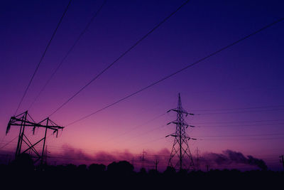 Low angle view of silhouette electricity pylon against sky at sunset