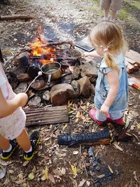 High angle view of siblings roasting marshmallows at campfire on field