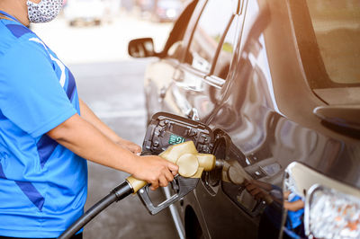 Midsection of man holding camera while standing by car