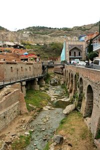 Arch bridge amidst buildings in city against sky